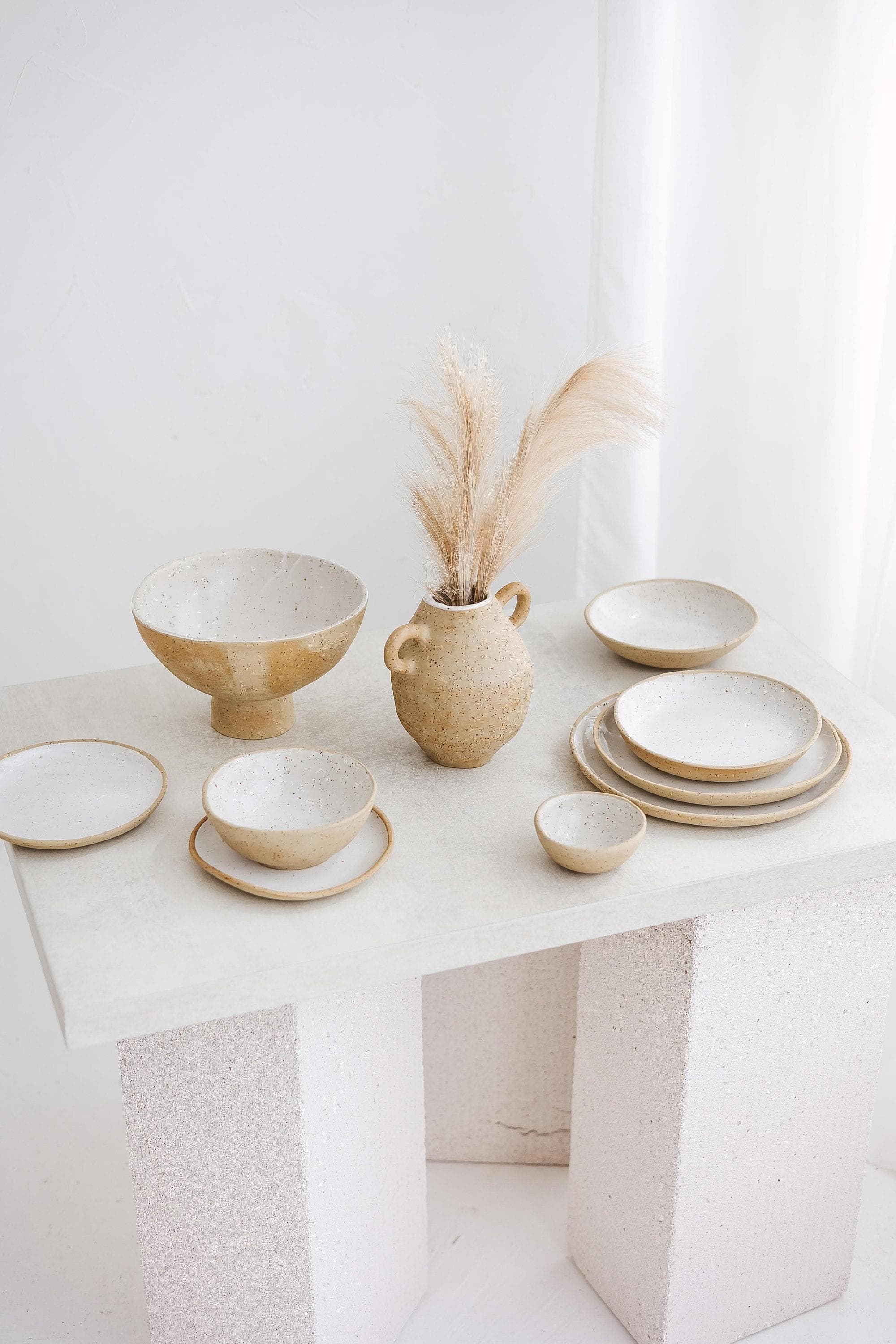 Handmade ceramic mug and vessels in a warm studio